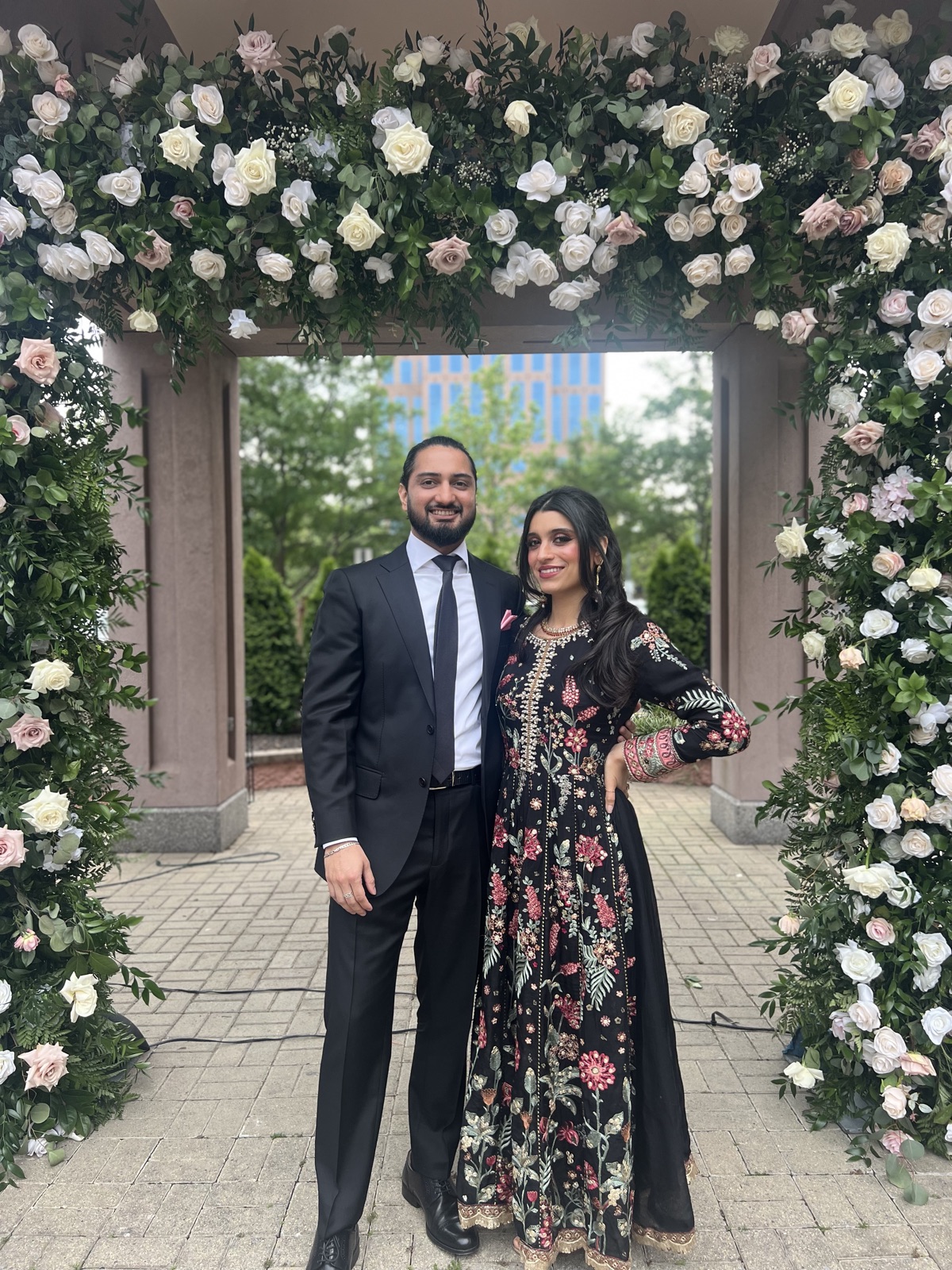 Jennifer and Samir beneath a floral arch